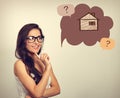 Beautiful thinking business woman in glasses looking on illustration house in bubble above with questions. Insurance protection c Royalty Free Stock Photo