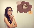 Beautiful thinking business woman in glasses looking on illustration house in bubble above with questions. Insurance protection c