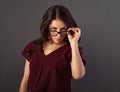 Beautiful thinking serious brunette business woman looking happy in eye glasses and holding spectacles in red silk blouse on grey Royalty Free Stock Photo