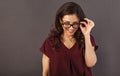 Beautiful thinking toothy smiling brunette business woman looking happy in eye glasses with curly hair style in red silk blouse on Royalty Free Stock Photo