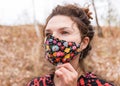 Beautiful thirty-year-old woman in colored mask outdoors