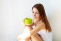 Beautiful thoughtful brunette girl drinks coffee sitting on the floor in an empty room against a white wall background Royalty Free Stock Photo