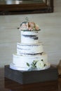 Beautiful three tiered wedding cake with roses and dirty icing Royalty Free Stock Photo