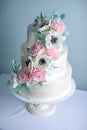 Beautiful three tiered white wedding cake decorated with flowers sugar pink peonies. Concept of elegant holiday desserts Royalty Free Stock Photo