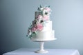 Beautiful three tiered white wedding cake decorated with flowers sugar pink peonies. Concept of elegant holiday desserts