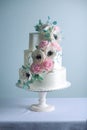 Beautiful three tiered white wedding cake decorated with flowers sugar pink peonies. Concept of elegant holiday desserts Royalty Free Stock Photo