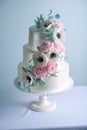 Beautiful three tiered white wedding cake decorated with flowers sugar pink peonies. Concept of elegant holiday desserts Royalty Free Stock Photo