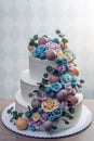 Beautiful three-tiered white wedding cake decorated with colorful flowers roses. Concept of elegant holiday desserts Royalty Free Stock Photo