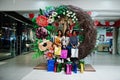 Beautiful three well-dressed afro american girls with colored shopping bags sitting on spring decoration photo zone in mall Royalty Free Stock Photo