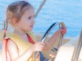 Beautiful three-year-old girl at the helm of a boat on a clear day