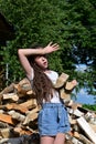 beautiful tired girl with long hair in white shirt puts firewood in pile. Concept of harvesting firewood for winter. Royalty Free Stock Photo