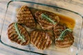 Beautiful toasted steaks in a glass plate on a wooden background, in their own juice and sprigs of rosemary. Royalty Free Stock Photo