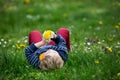 Beautiful toddler blond child, cute boy, lying in the grass in daisy and dandelions filed Royalty Free Stock Photo