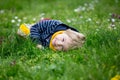 Beautiful toddler blond child, cute boy, lying in the grass in daisy and dandelions filed Royalty Free Stock Photo