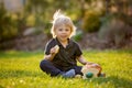 Beautiful toddler boy, eating sweet bread and eggs in garden on sunset, little chicks running around Royalty Free Stock Photo