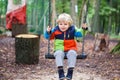 Beautiful toddler boy having fun on swing in autumn forest Royalty Free Stock Photo