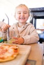 Beautiful toddler child girl sitting on baby highchair drinking juice using straw with happy face Royalty Free Stock Photo