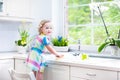 Beautiful toddler girl in colorful dress washing dishes Royalty Free Stock Photo