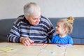 Beautiful toddler girl and grandfather playing together pictures lotto table cards game at home. Cute child and senior Royalty Free Stock Photo