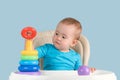 A beautiful toddler of 12-17 months is learning to assemble a pyramid of colored rings in the correct order, selective focus