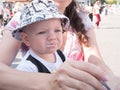 Beautiful toddler walking with his mother on a city holiday. Boy eating soup sour cream the street. Kid stylishly Royalty Free Stock Photo