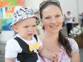 Beautiful toddler walking with his mother on a city holiday. Kid stylishly dressed butterfly and cap Royalty Free Stock Photo