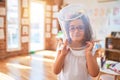 Beautiful toddler wearing glasses, unicorn diadem and plastic cube on head playing as astronaut at kindergarten