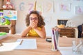 Beautiful toddler wearing glasses and unicorn diadem sitting on desk at kindergarten shocked covering mouth with hands for mistake Royalty Free Stock Photo