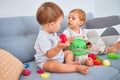 Beautiful toddlers sitting on the sofa playing with toys at home