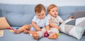 Beautiful toddlers sitting on the sofa playing with toys at home