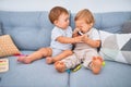 Beautiful toddlers sitting on the sofa playing with toys at home