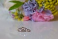Beautiful toned picture with Engagement rings lie on a wooden surface against the background of a bouquet of flowers . wedding Royalty Free Stock Photo