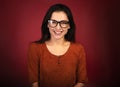 Beautiful toothy laughing woman  looking happy in eye glasses in casual orange t-shirt on red background with empty copy space. Royalty Free Stock Photo