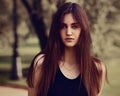 Beautiful toothy smiling teen brunette woman looking happy outdoors on summer green trees background. Closeup portrait in bright Royalty Free Stock Photo