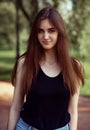 Beautiful toothy smiling teen woman looking happy outdoors in black t-shirt on summer green trees background. Closeup portrait in Royalty Free Stock Photo