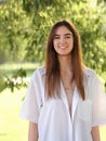 Beautiful toothy smiling teen woman looking happy outdoors summer green trees background. Closeup portrait in bright sunny day Royalty Free Stock Photo