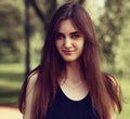 Beautiful toothy smiling teen woman looking happy outdoors on summer green trees background. Closeup portrait in bright sunny day Royalty Free Stock Photo