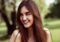 Beautiful toothy smiling teen woman looking happy outdoors on summer green trees background. Closeup portrait in bright sunny day Royalty Free Stock Photo