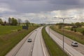 Beautiful top view of E4 highway with several cars. Green side fields and stormy sky background.