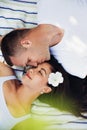 Beautiful couple in love lying on a picnic blanket. Happy caucasian man kiss his woman with white flower in hair Royalty Free Stock Photo