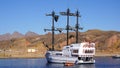 Beautiful tourist ship on the background of the sandy shore and mountains. Medieval old ship. Royalty Free Stock Photo