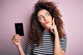 Beautiful tourist woman with curly hair and piercing holding australia australian passport id serious face thinking about