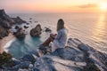 Beautiful tourist women enjoying sunset at Praia da Ursa Beach. Surreal scenery of Sintra, Portugal. Atlantic Ocean