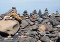 Beautiful towers of stacked pebbles and stones in a large arrangement on a black sand beach with blue sky