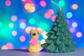 Beautiful toy rat made of plasticine and a candle in the shape of a Christmas tree on the background of colored lights from a Royalty Free Stock Photo