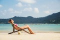 Beautiful, tranquil lady tanning while lying in the lounge with a fruit cocktail on the beach