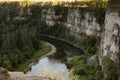 Beautiful tranquil mountain canyon landscape with rocky cliffs and precipice with river below and lush green forest in bright gold Royalty Free Stock Photo