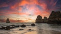Mesmerizing calm pink sunset over the rocky shoreline of the Camilo Beach in Algarve