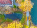 Beautiful travel or tourism style look down aerial of pedestrian foot bridge across River at park with colorful fall foliage