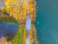 Beautiful travel or tourism style look down aerial of pedestrian foot bridge across River at park with colorful fall foliage